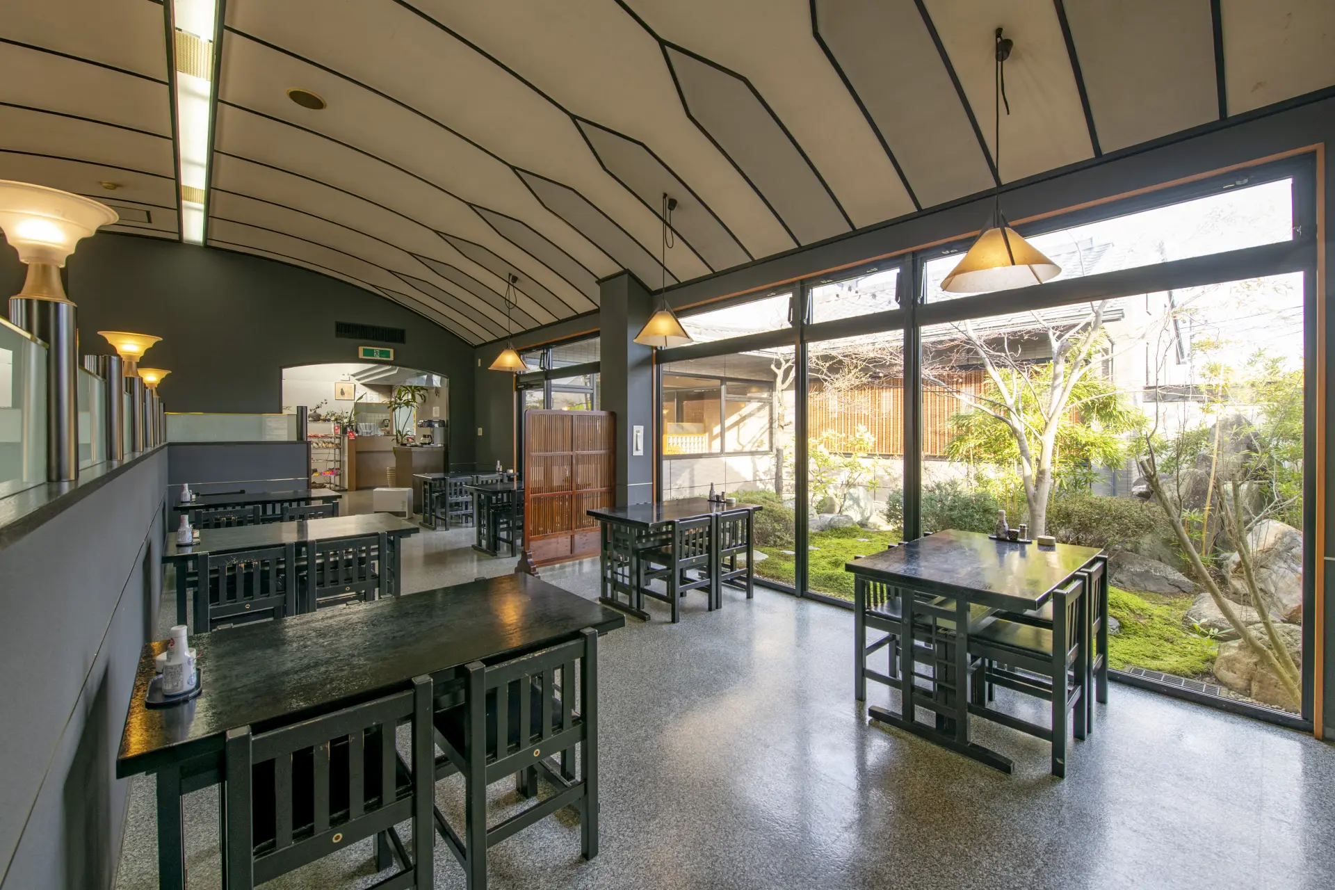 The restaurant features table seating with large windows overlooking the garden, as well as raised tatami seating, providing a cozy and traditional dining experience.