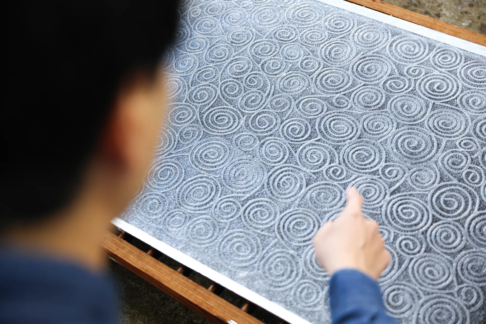 Using a metal mold, participants create their own original patterns on the washi, adding a unique personal touch to their handmade paper.