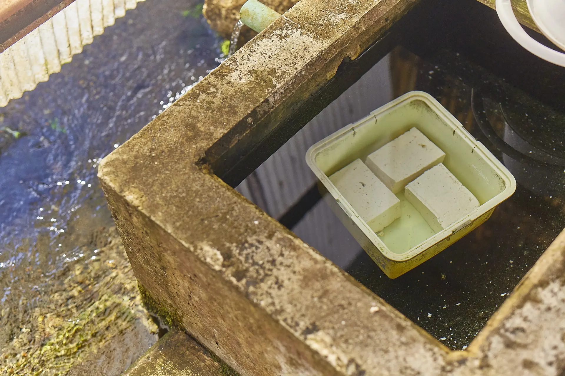 Tofu chilled in the fresh spring water of a kabata. It also doubles as a hub for food prep.