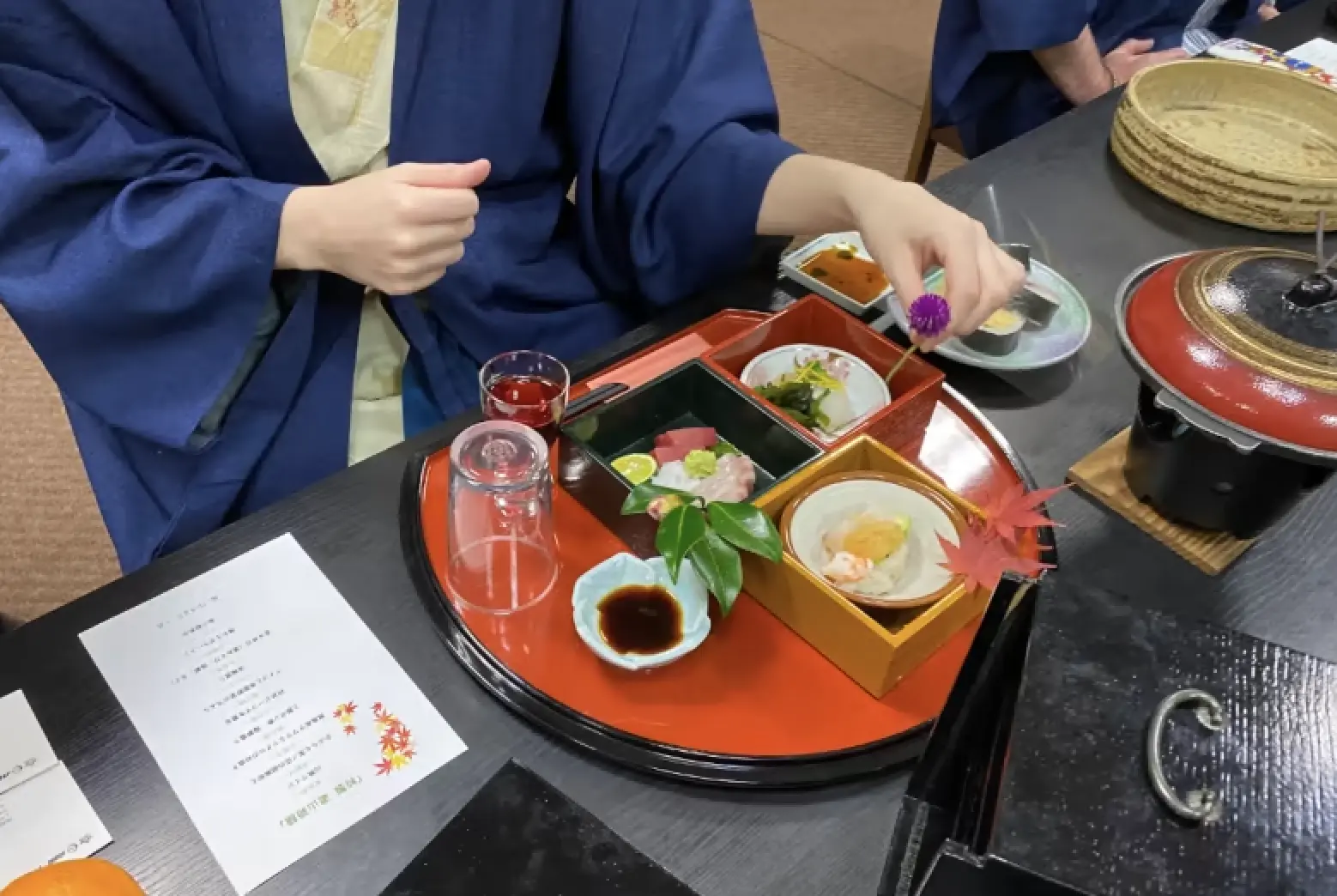 Decorating a traditional jubako box with seasonal foliage from Kamikatsu’s fields and mountains, experiencing the aesthetics of Japanese cuisine.